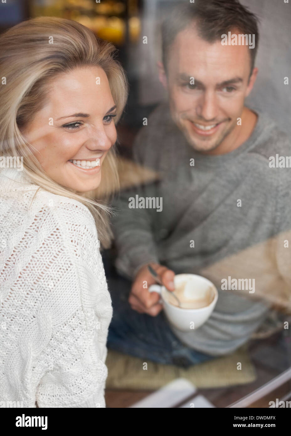 Happy couple looking out of cafe window while having coffee Stock Photo