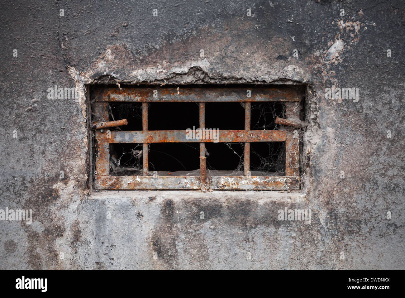 Small dark basement window with rusted steel lattice Stock Photo