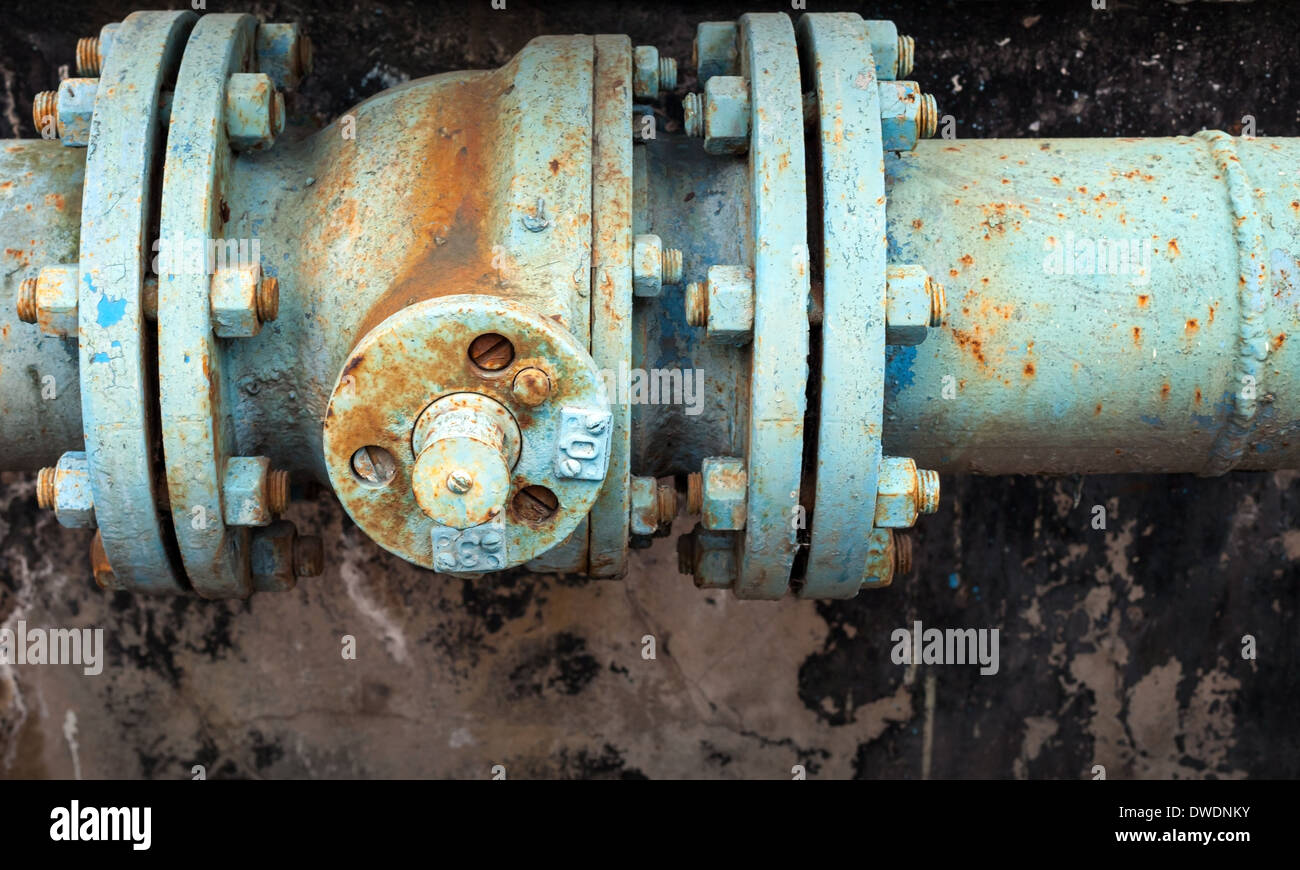 Old rusted valve on blue industrial pipeline Stock Photo