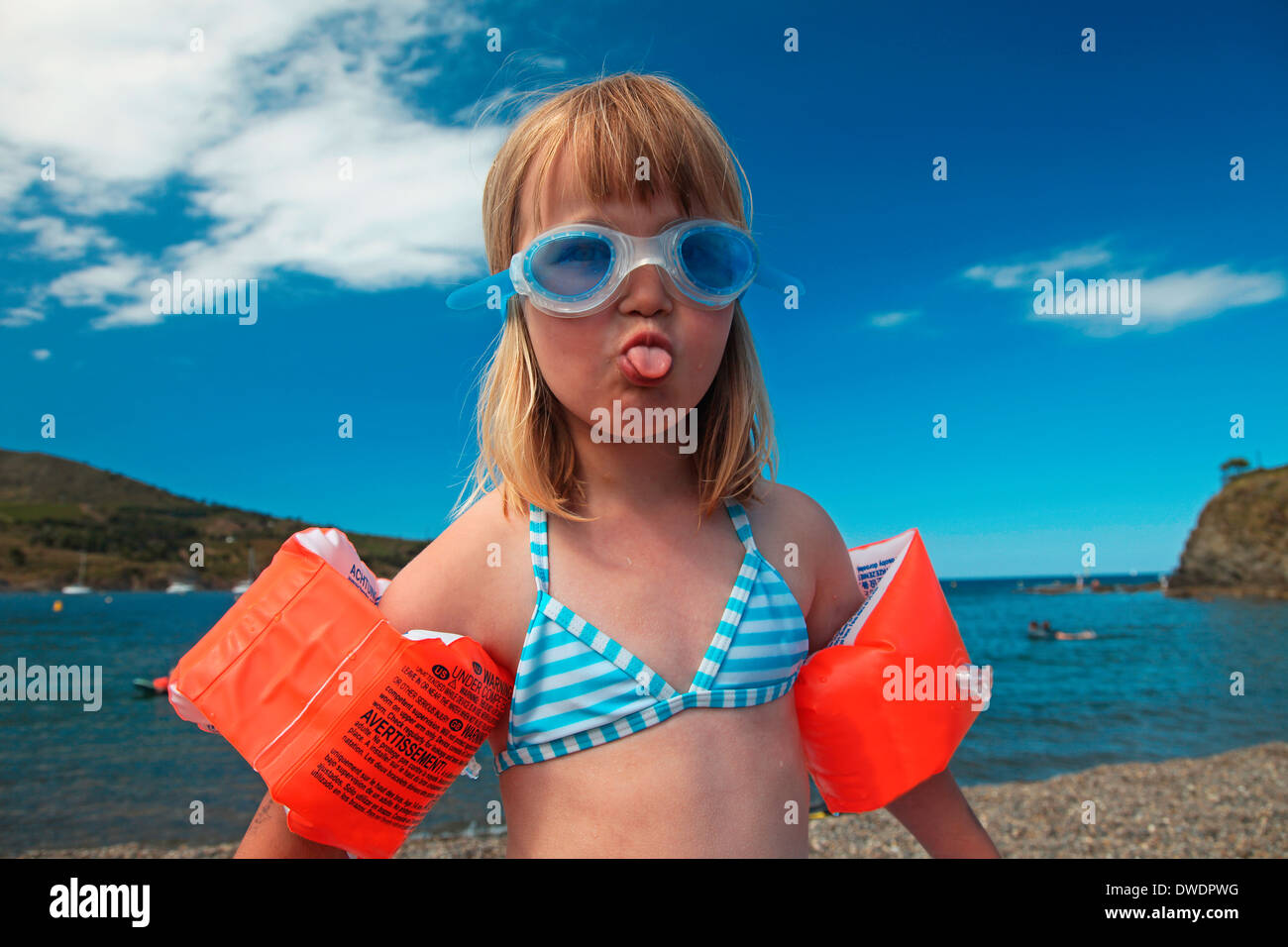 France, Southern France, portrait of little girl with swimming goggles and  water wings stretching out tongue Stock Photo - Alamy