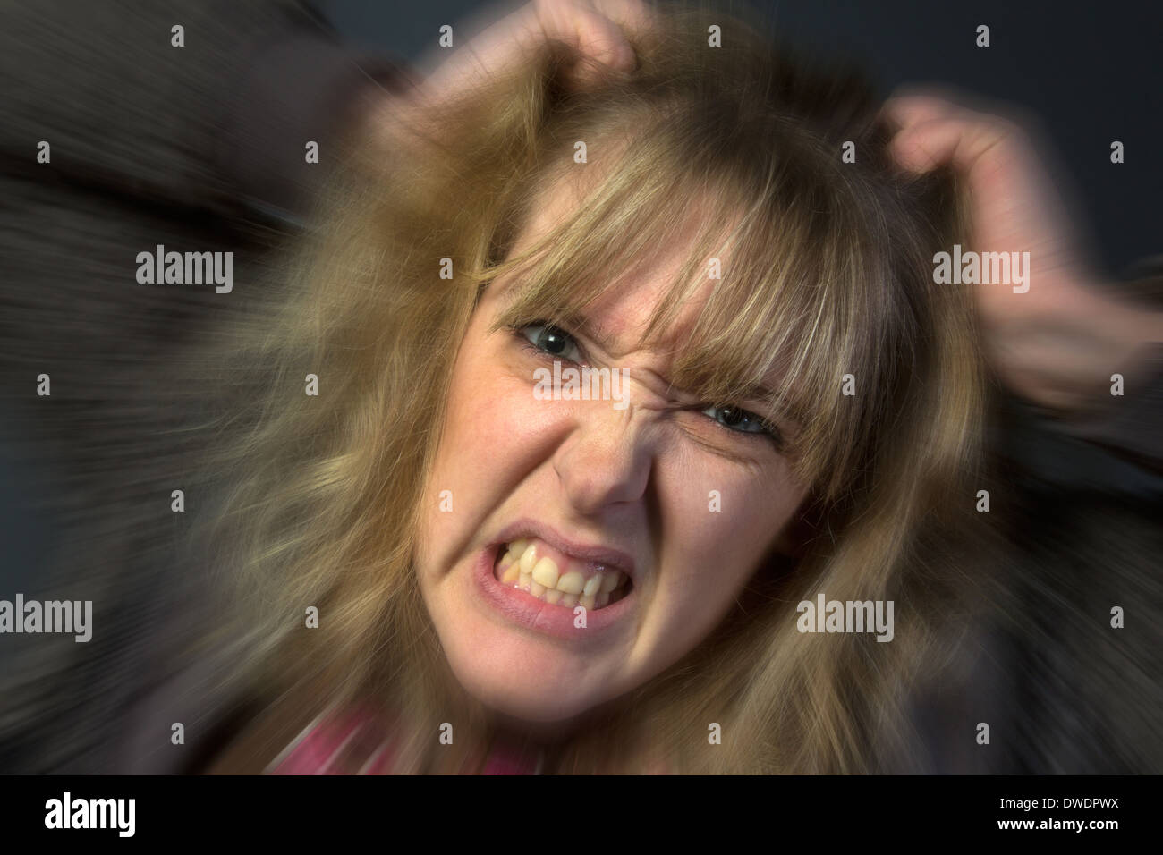 A very angry young woman tearing her hair out. Stock Photo