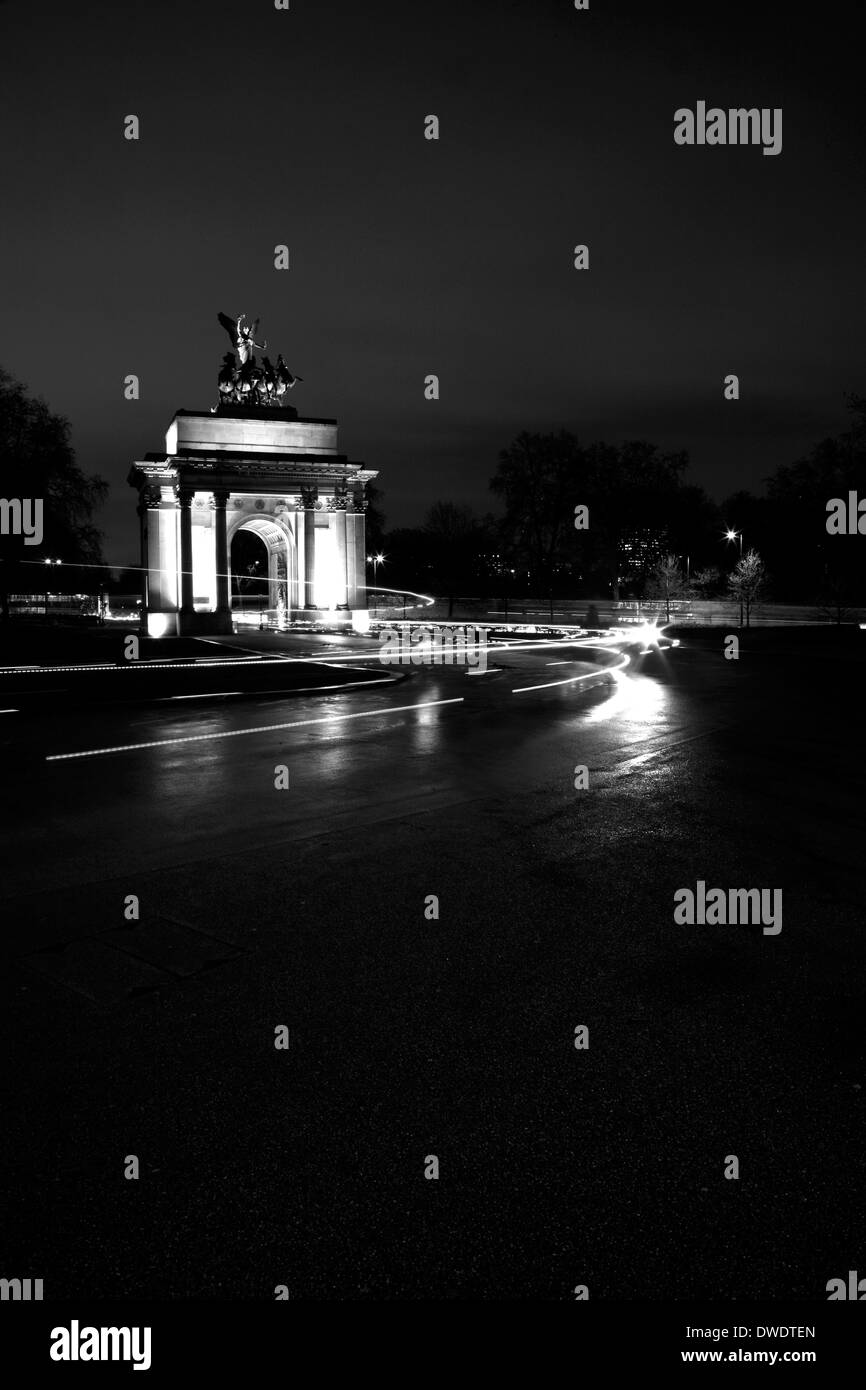 Trail lights of cyclists passing through Wellington Arch, Hyde Park Corner, London, UK Stock Photo