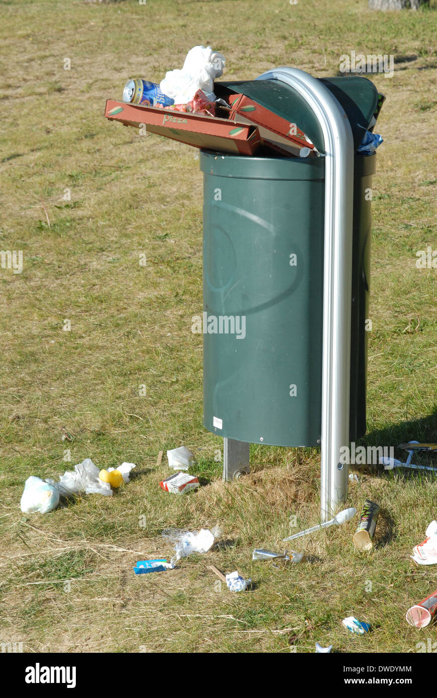 Full rubbish bin, rubbish scattered on grass. Stock Photo