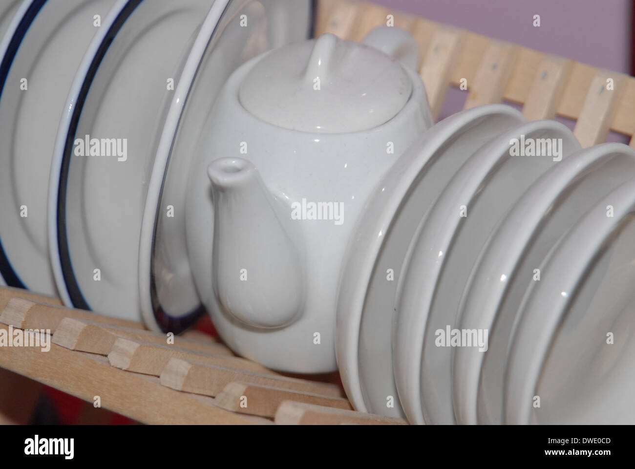 Childrens white porcelain tea set in a wooden dish rack. Saucers with blue rim. Stock Photo