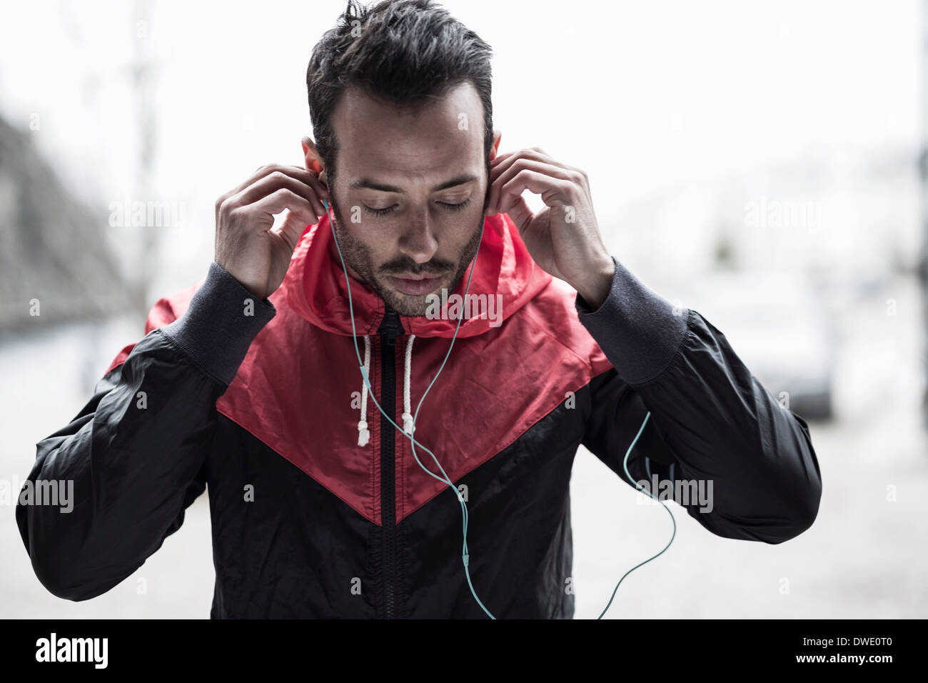Sporty man in jacket adjusting headphones Stock Photo