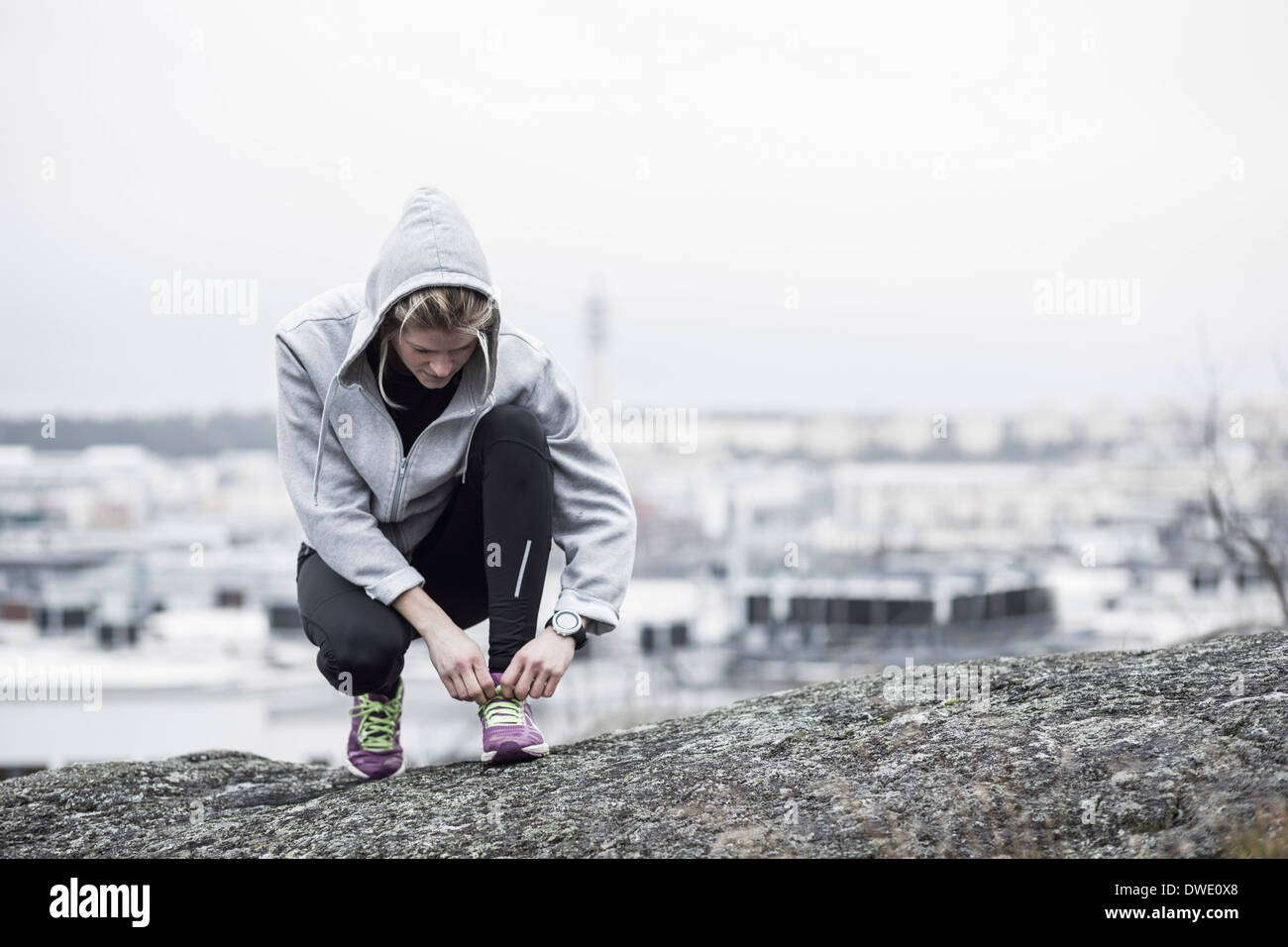 Full length of sporty woman tying shoe lace on rock Stock Photo