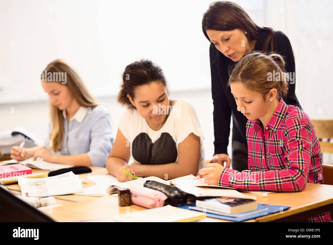 Mature female teacher teaching schoolgirls in classroom Stock Photo