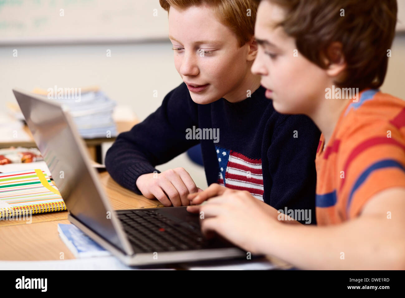 High school boys using laptop at desk in classroom Stock Photo