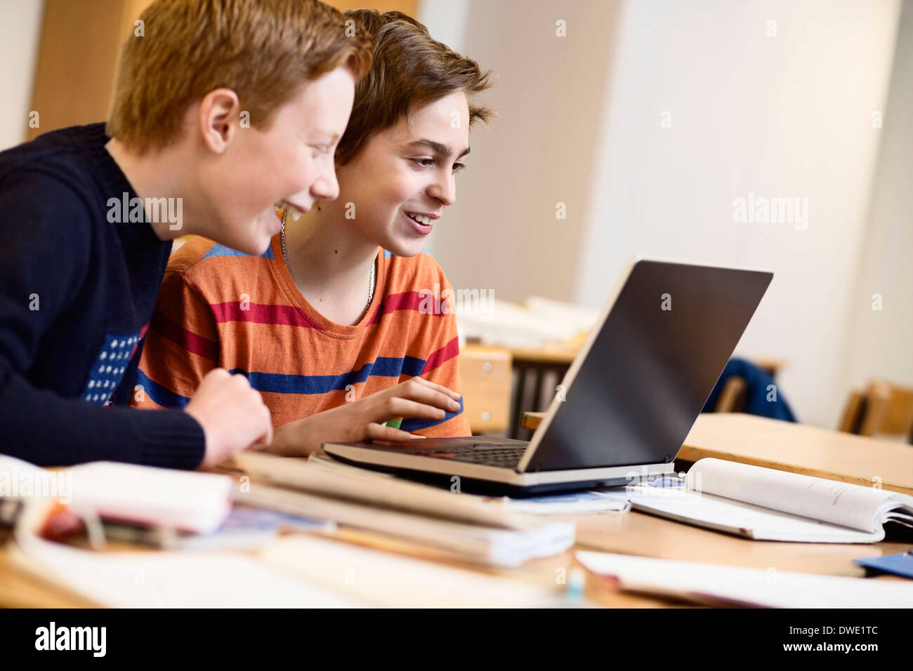 Schoolboys using laptop together in classroom Stock Photo