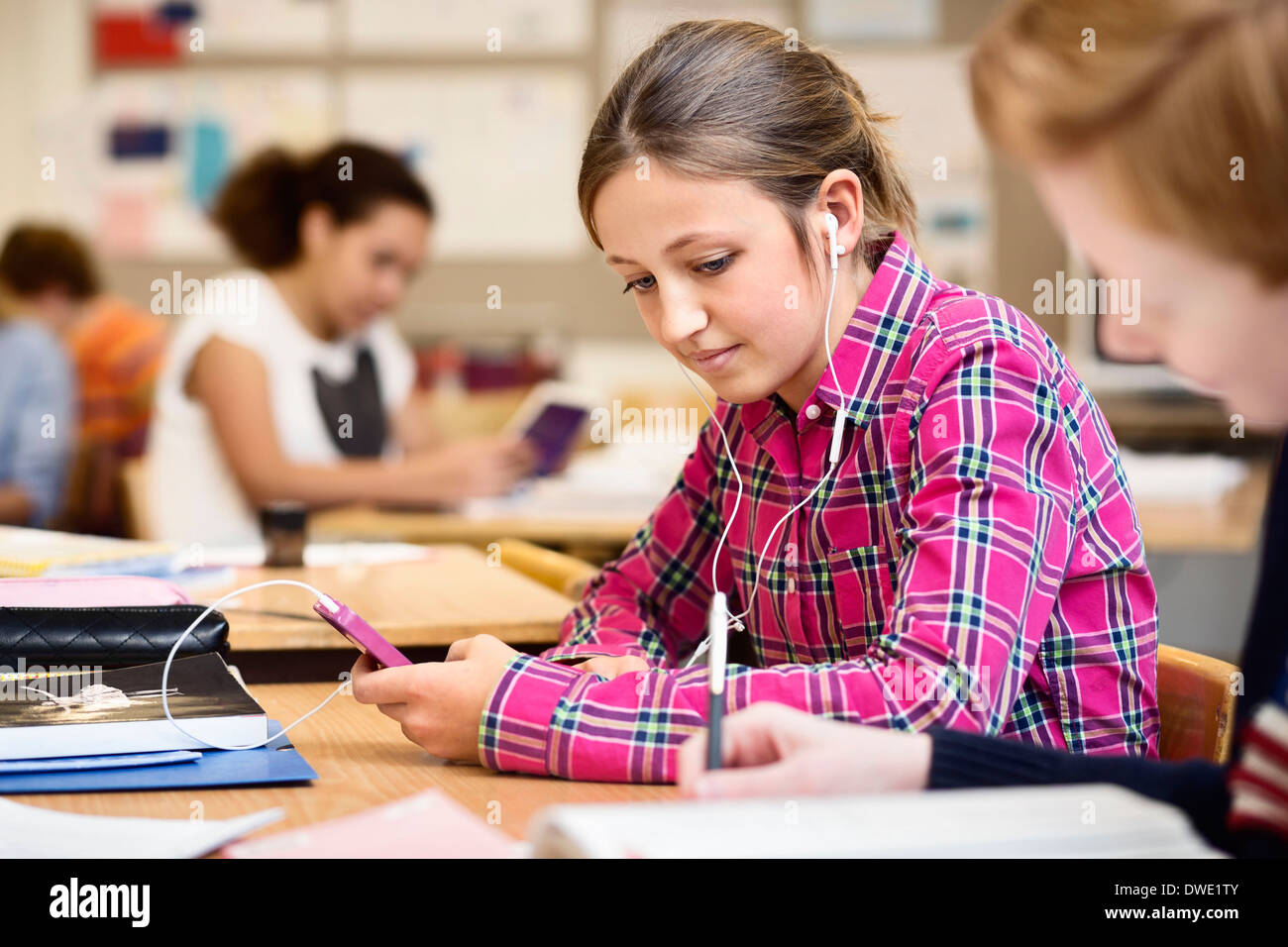 Schoolgirl listening music through smart phone in classroom Stock Photo