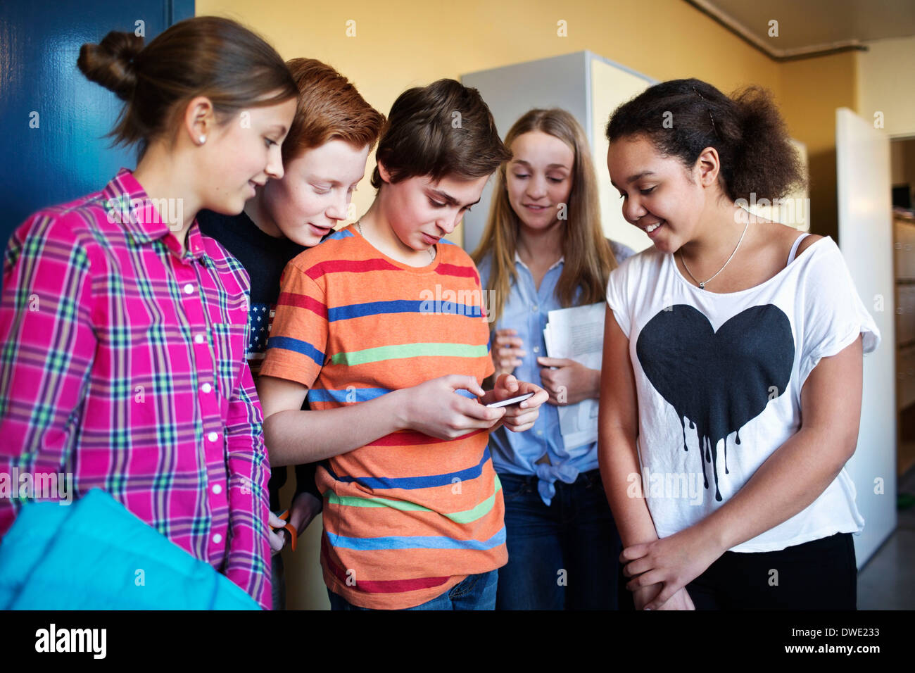 High school students using mobile phone in locker room Stock Photo