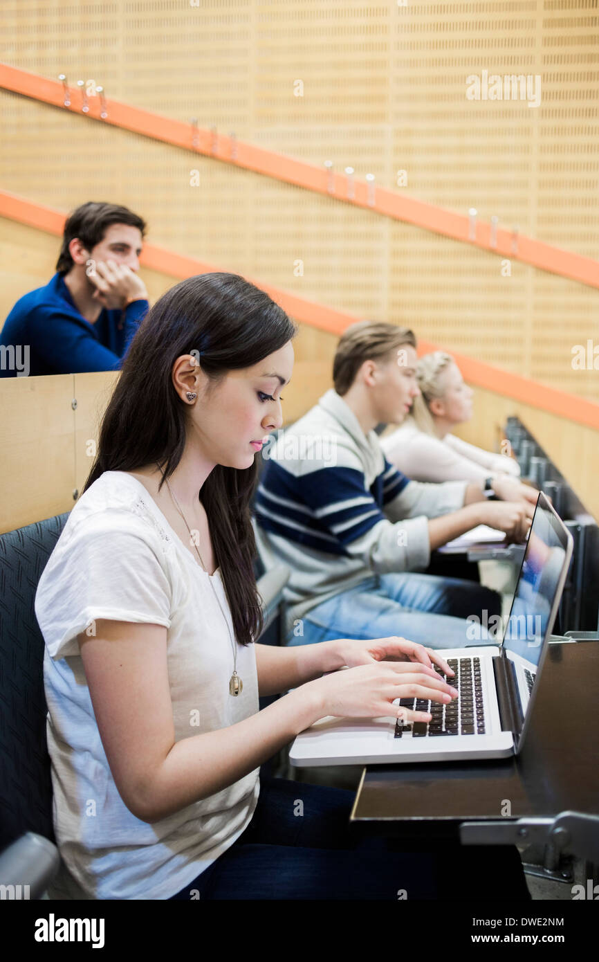 Side view of female university student using laptop in classroom Stock Photo