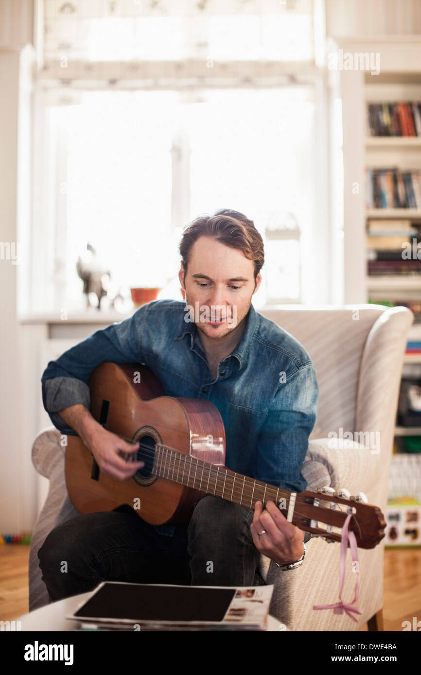 Mid adult man playing guitar at home Stock Photo