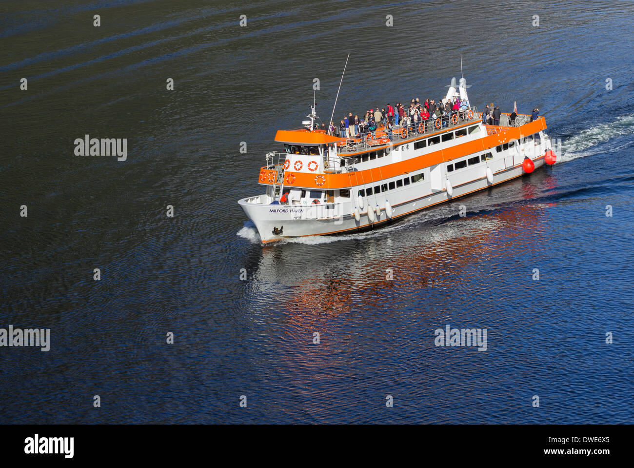 Tourists on Milford Haven ferry boat sailing into Milford Sound on South Island of New Zealand in early morning Stock Photo