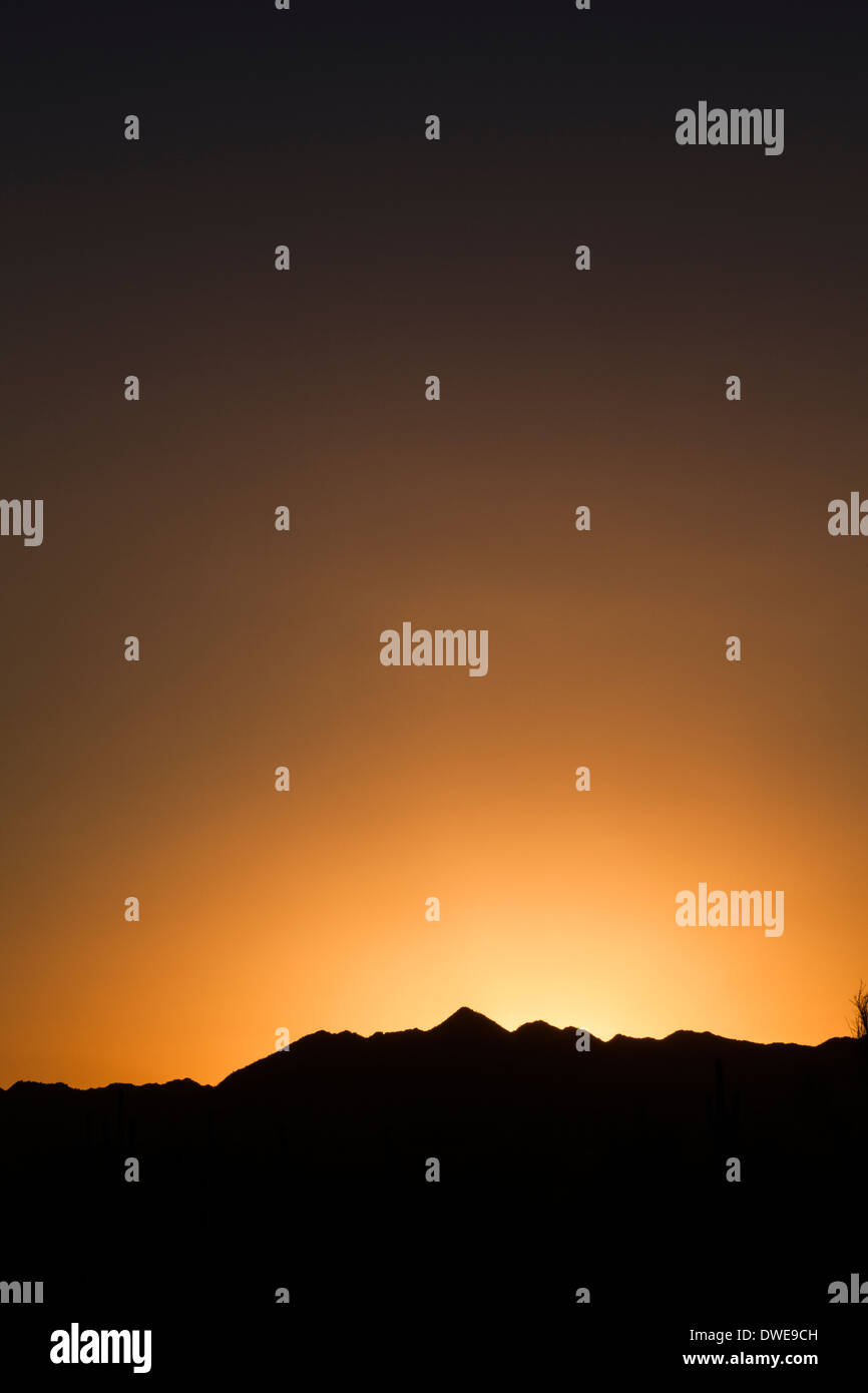 Silhouette of a desert mountain skyline at sunset. Stock Photo