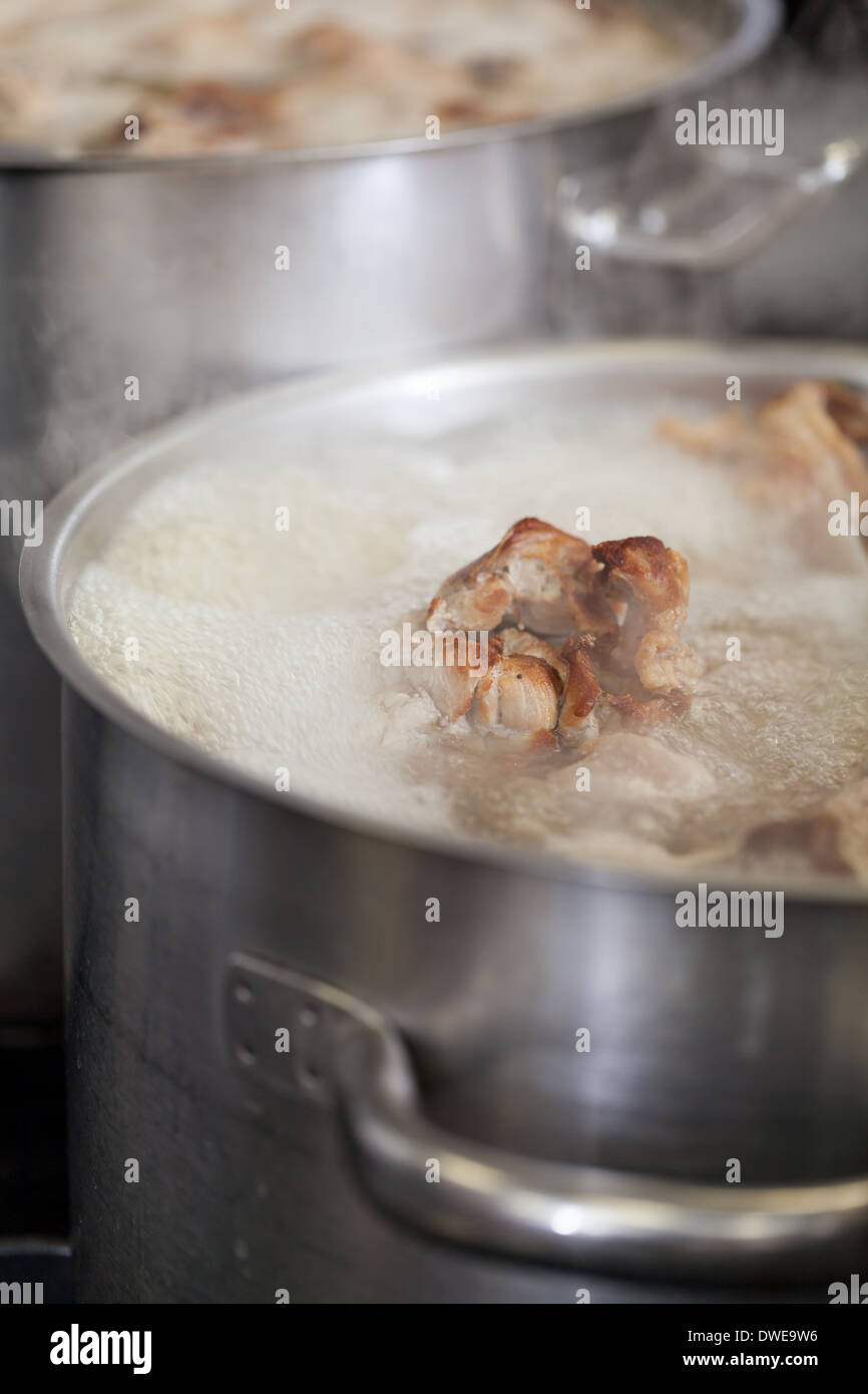 Cooking in a commercial kitchen with large stainless steel pots filled