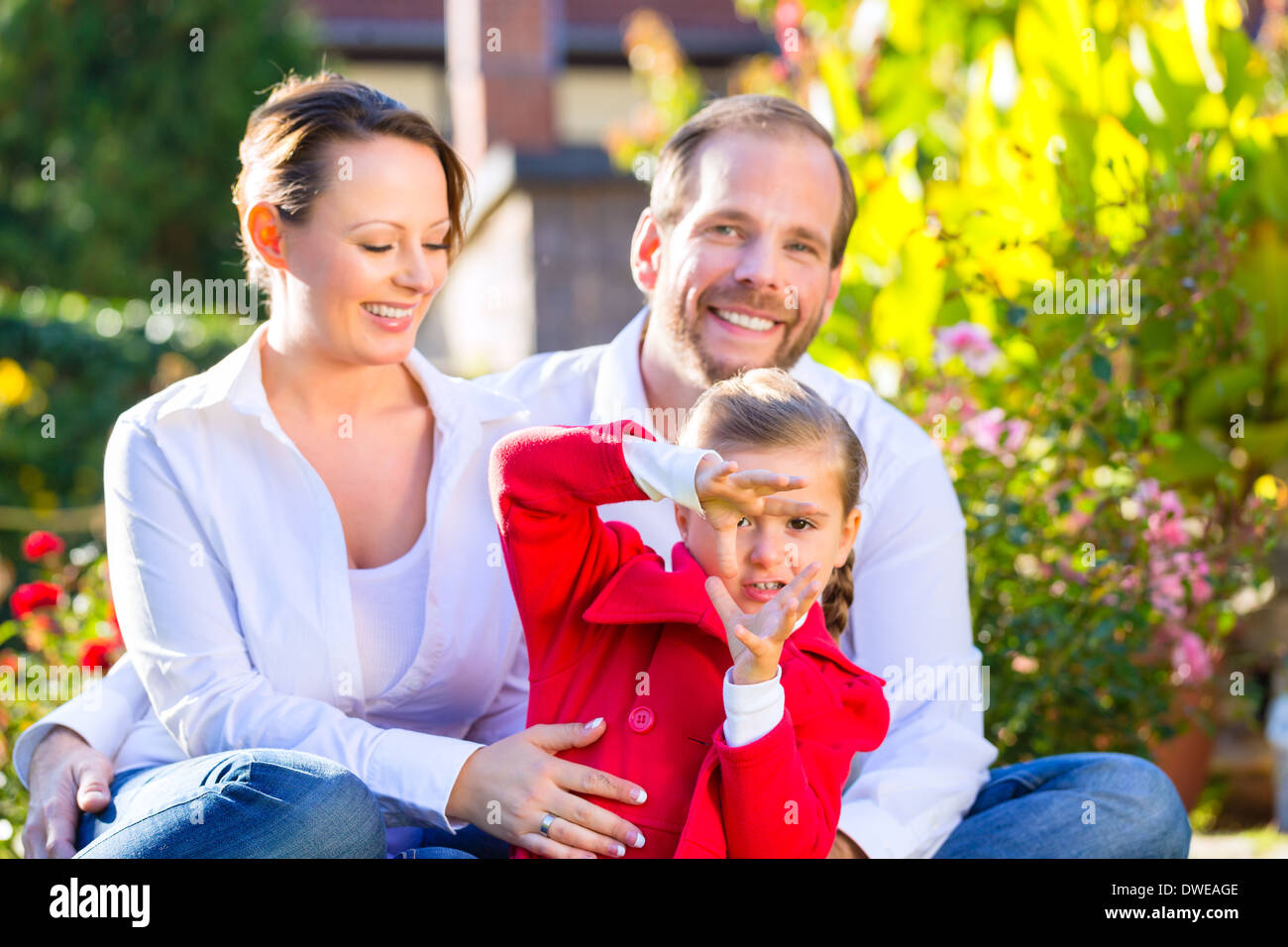 Family with mother, father and daughter together in the garden meadow Stock Photo
