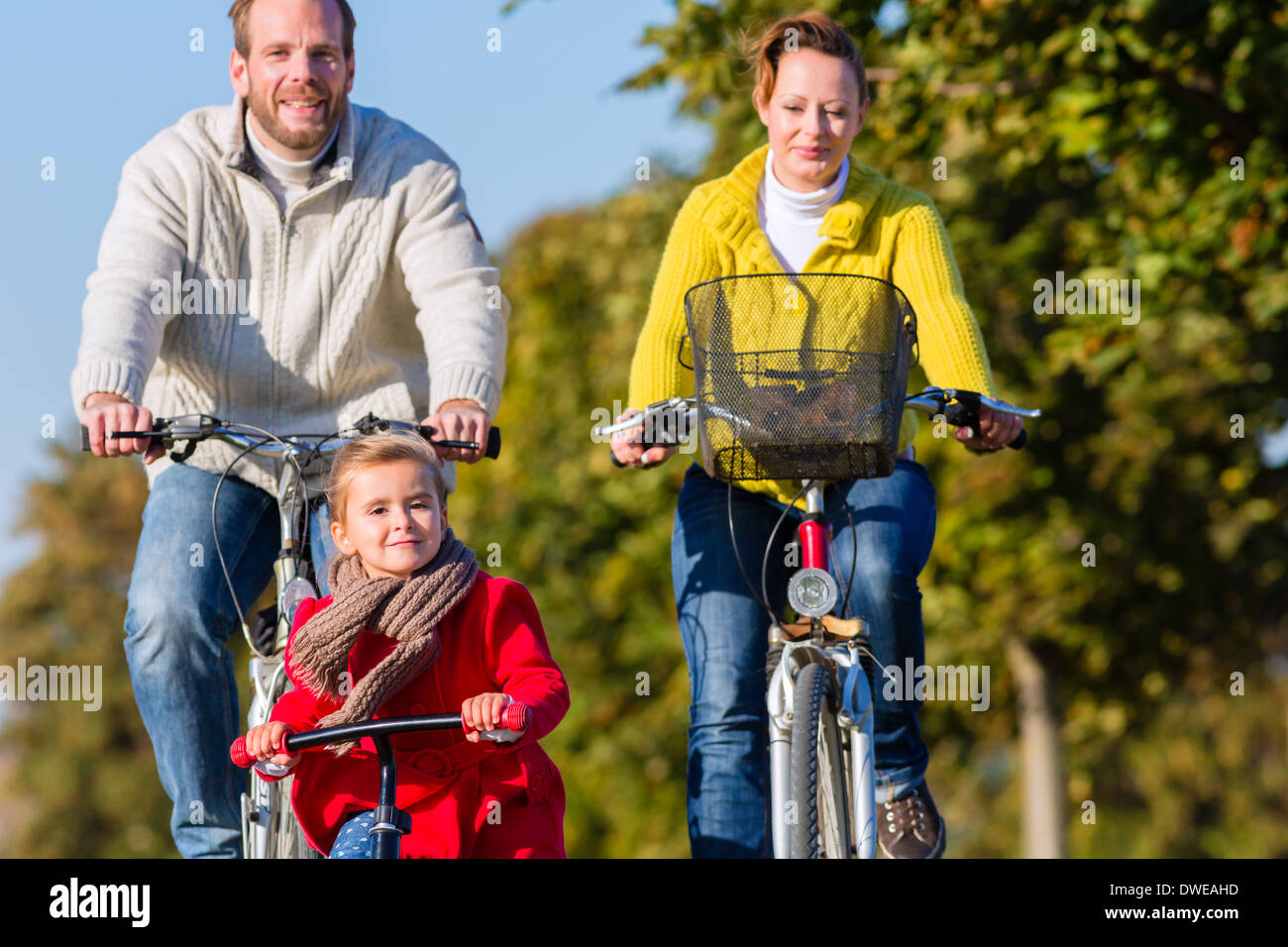Family with mother, father and daughter having family trip on bicycle or cycle in park Stock Photo