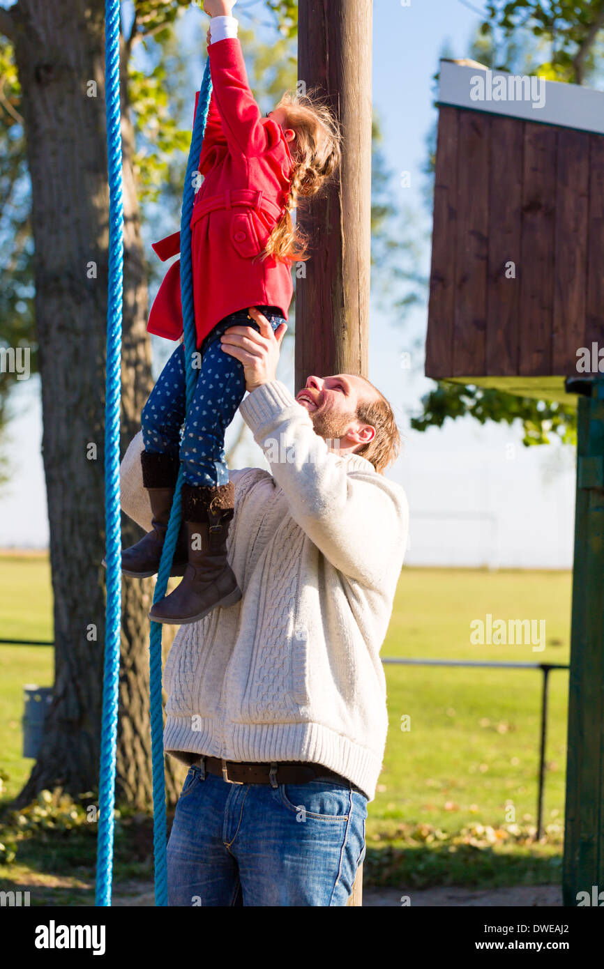 Family with Father and daughter climbing and playing on play area or court Stock Photo