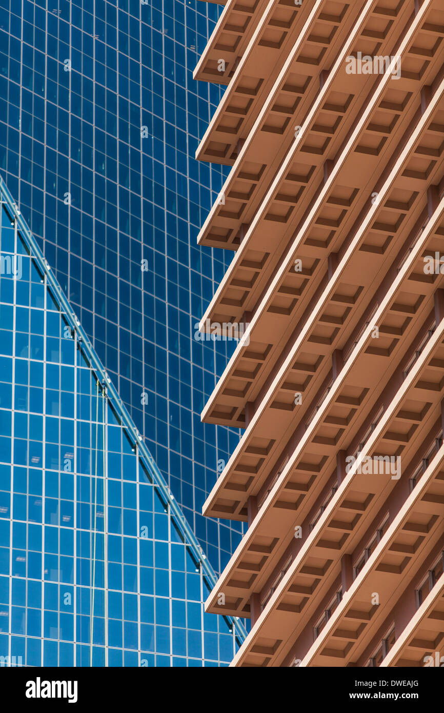 An abstract detail contrasting 2 different styles of building. A sleek all glass skyscraper looks on to a more traditional one. Stock Photo