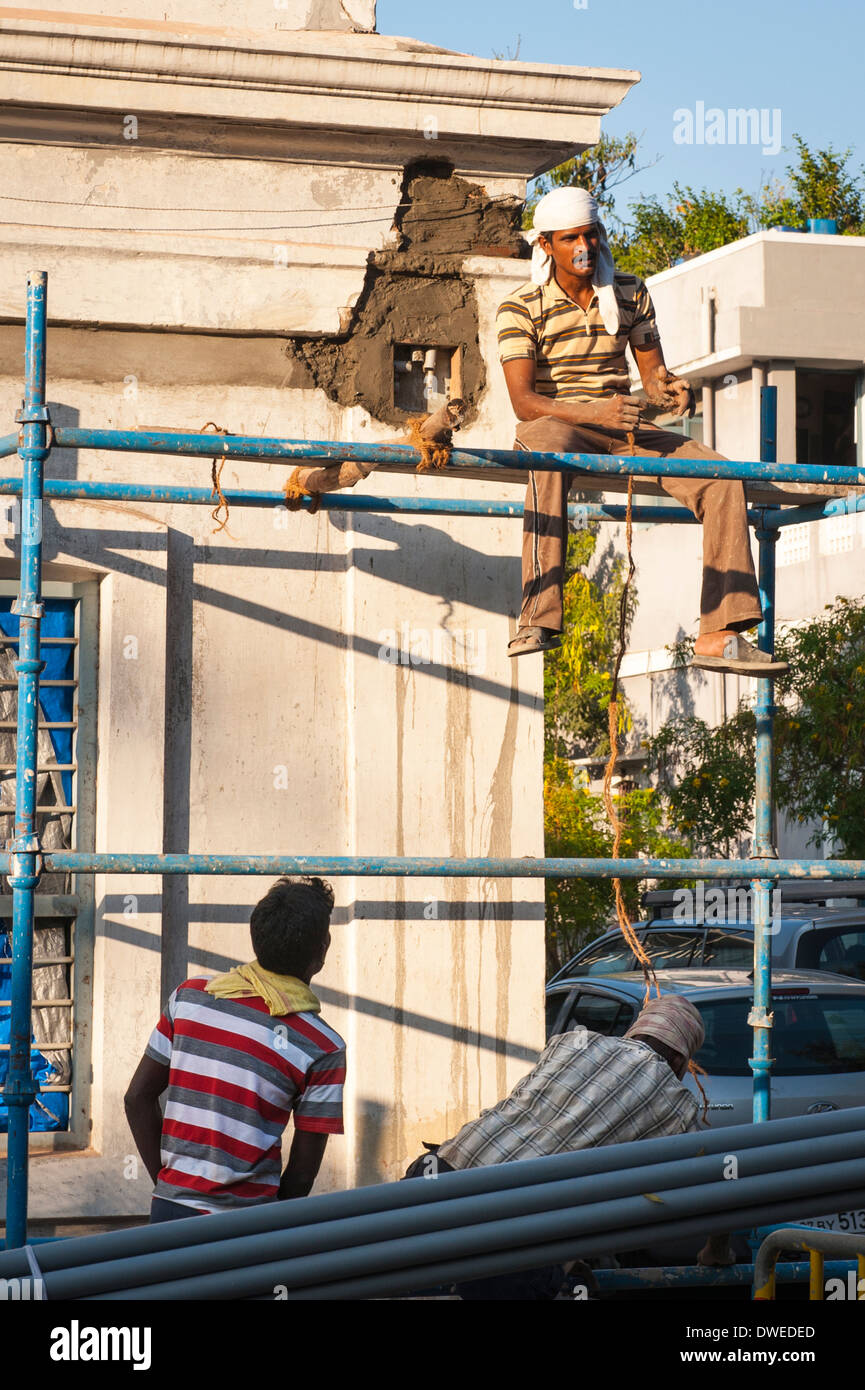 India Tamil Nadu Pondicherry Puducherry workmen workman builder builders scaffold scaffolding wall repair maintenance street scene trees tree men cars Stock Photo