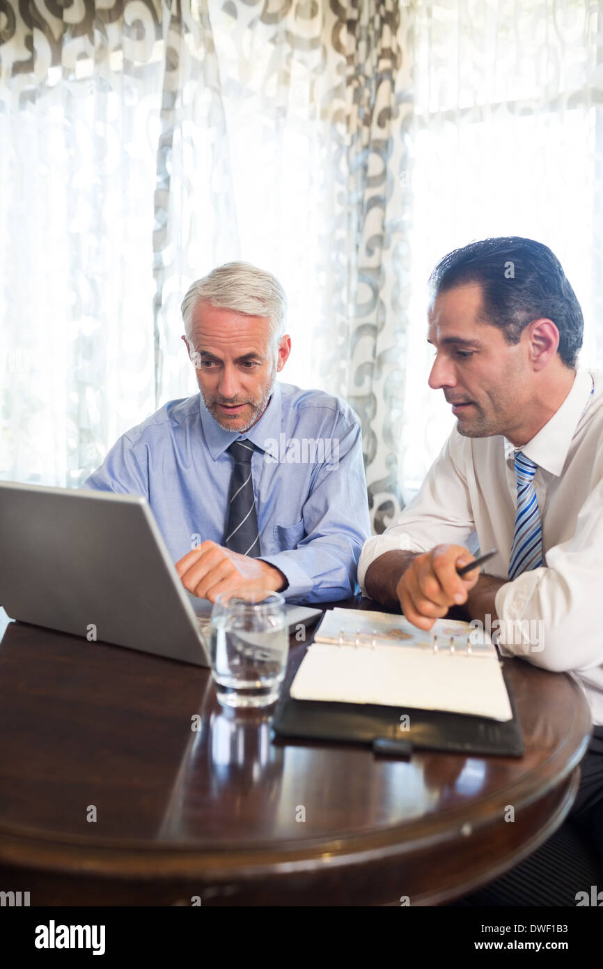 Businessmen using laptop at office desk Stock Photo