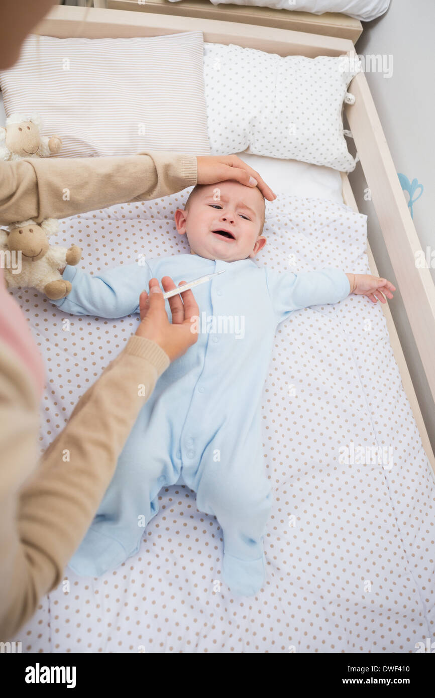 Mother checking ailing babys temperature Stock Photo