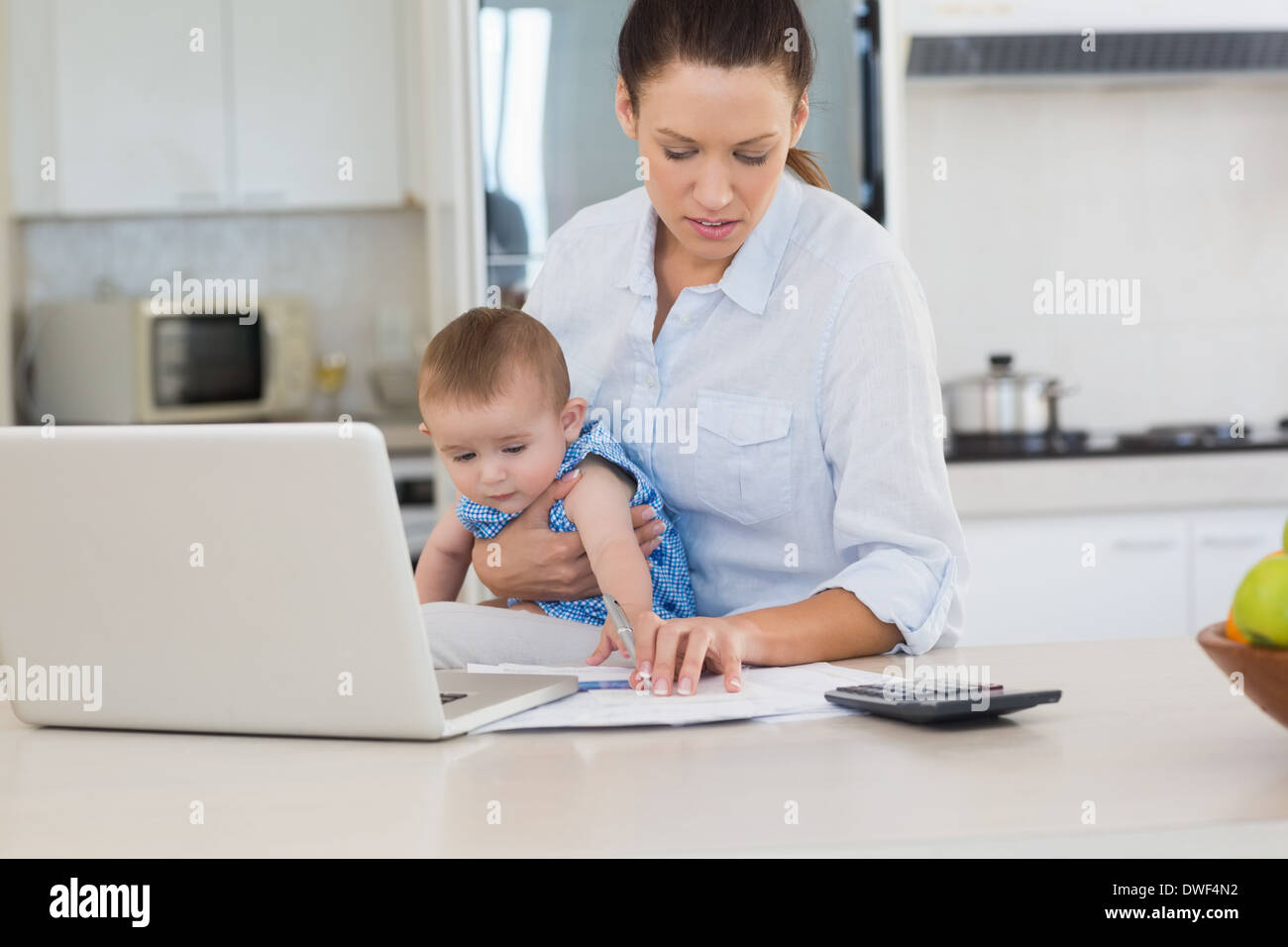 Mother holding baby while calculating home finances Stock Photo