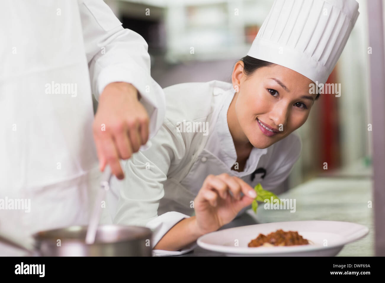 Happy chef putting basil leaf on spaghetti dish Stock Photo