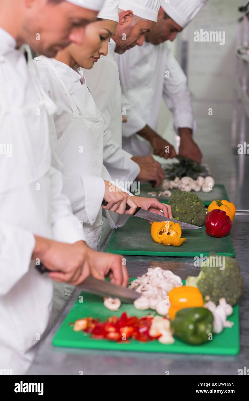 Row of trainee chefs slicing vegetables Stock Photo