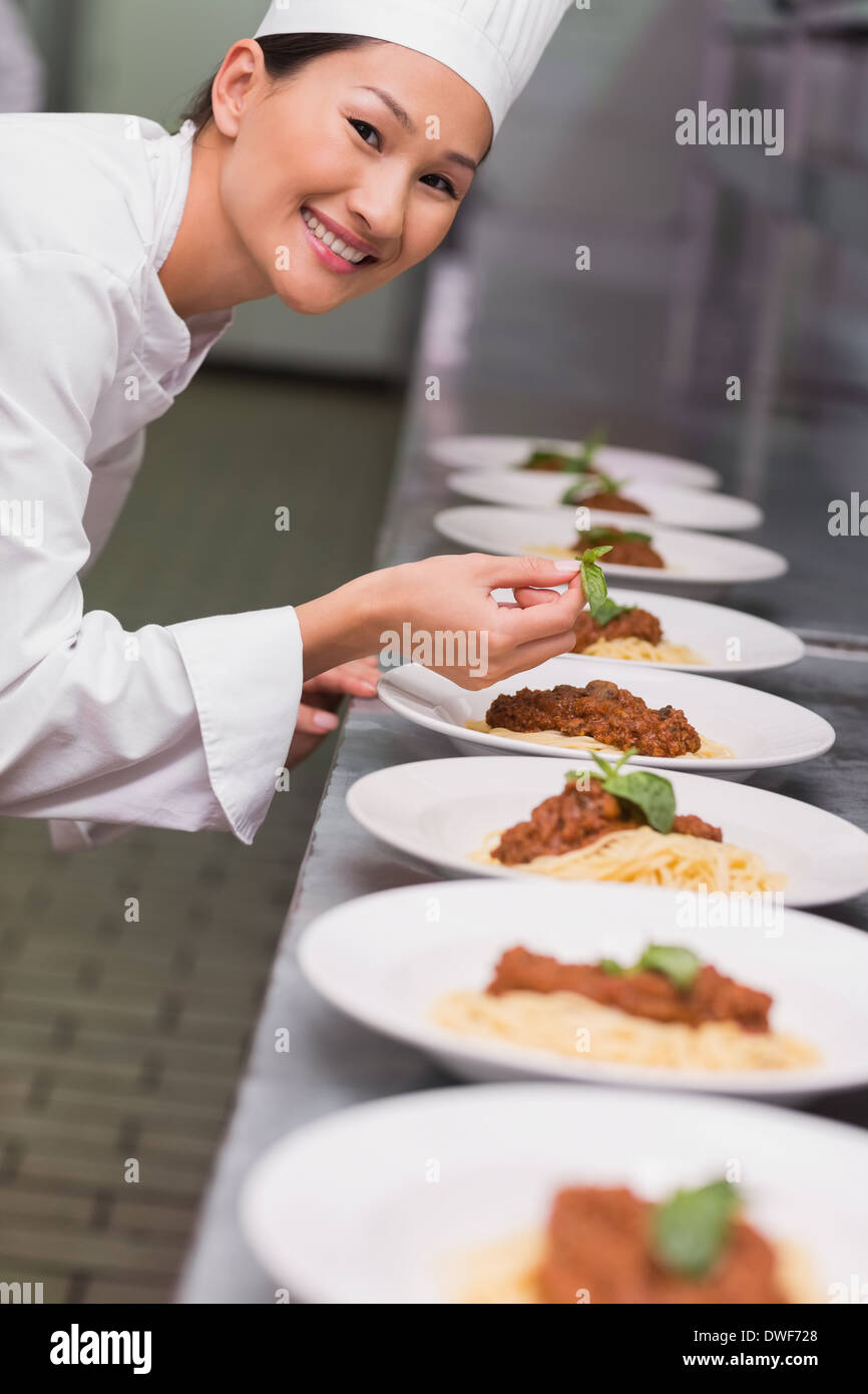 Happy chef putting basil leaf on spaghetti dish Stock Photo