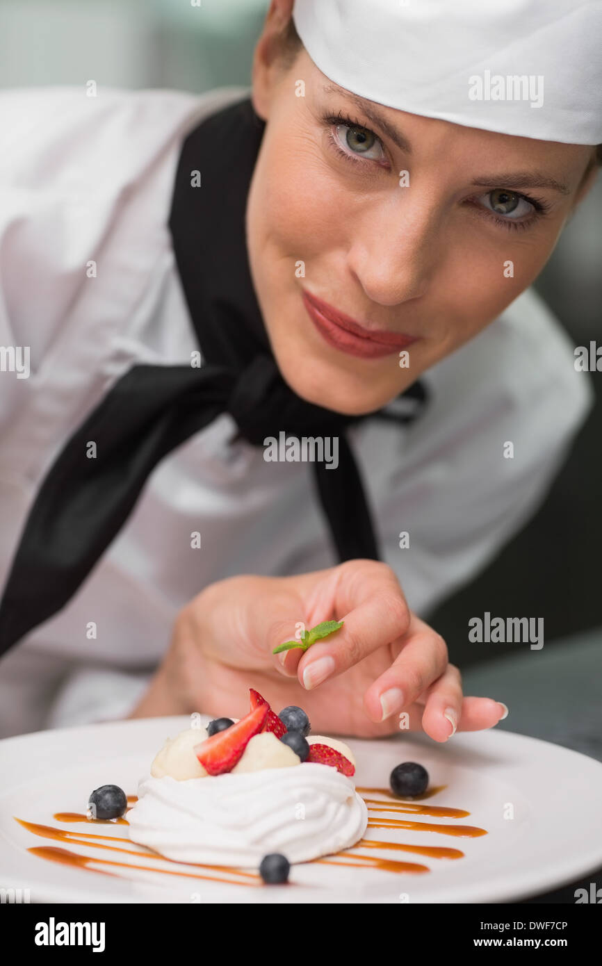 Smiling chef putting mint leaf on meringue dish Stock Photo