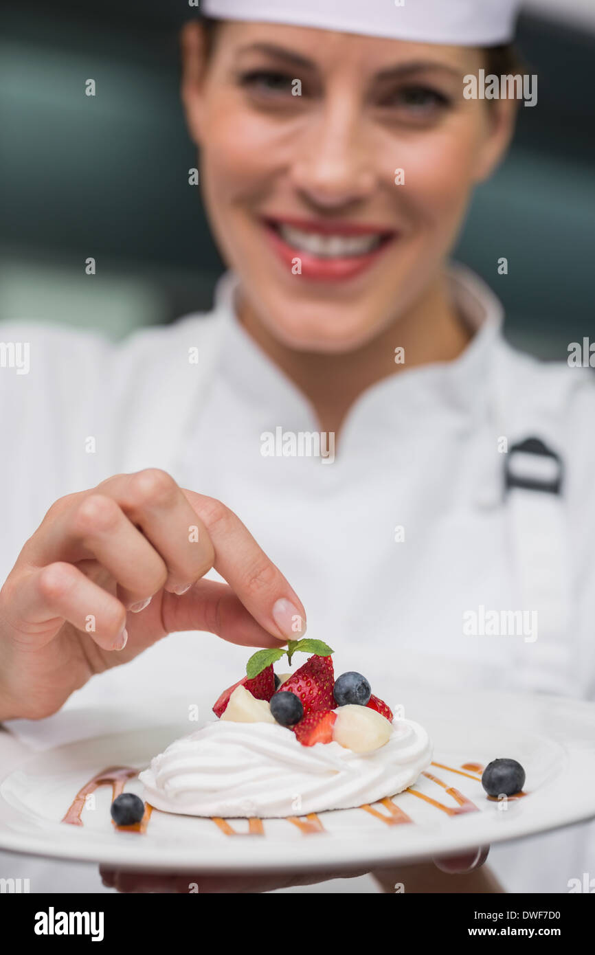 Smiling chef putting mint leaf on meringue dish Stock Photo