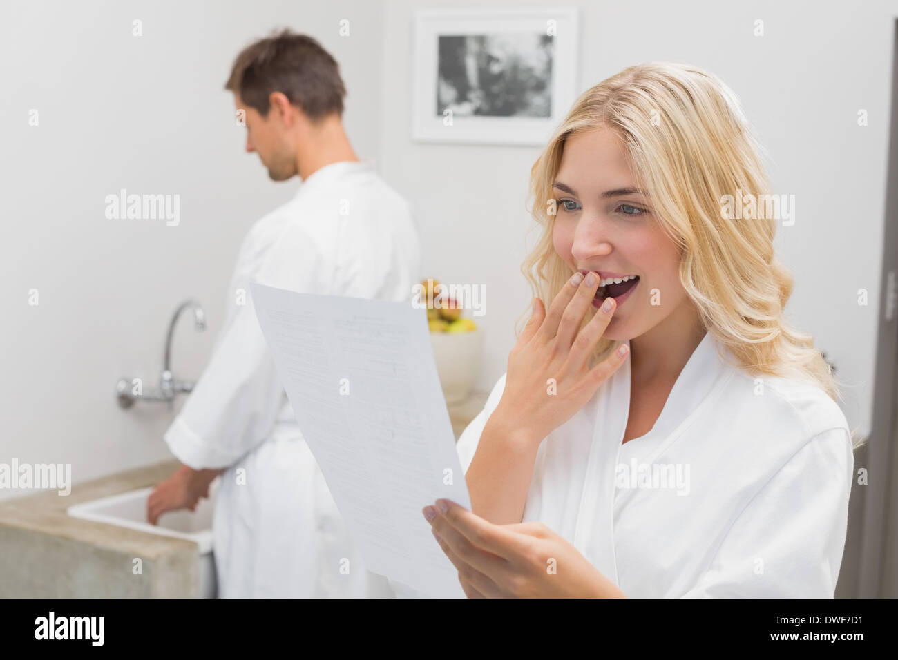Surprised woman looking at document with man in kitchen Stock Photo