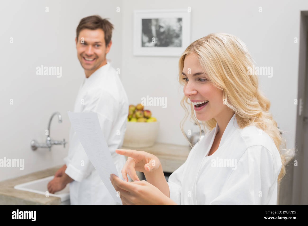 Surprised woman looking at document with man in kitchen Stock Photo