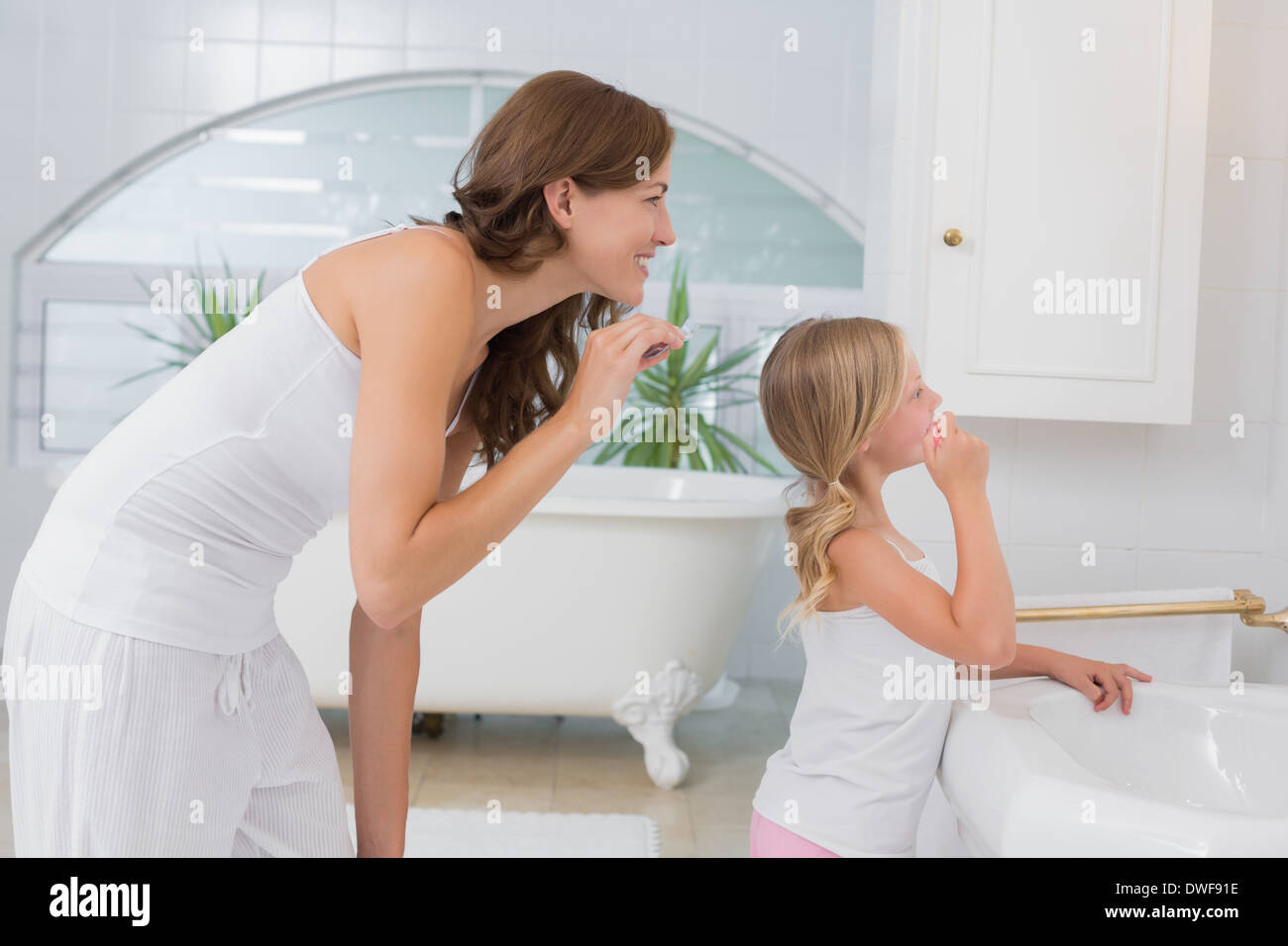 Little girl brushing teeth with mother Stock Photo