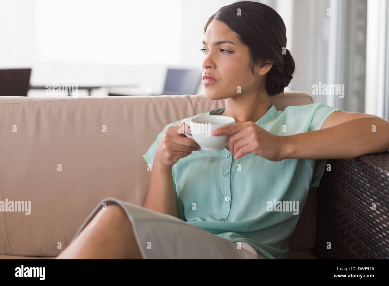 Thoughtful businesswoman having coffee sitting on sofa Stock Photo