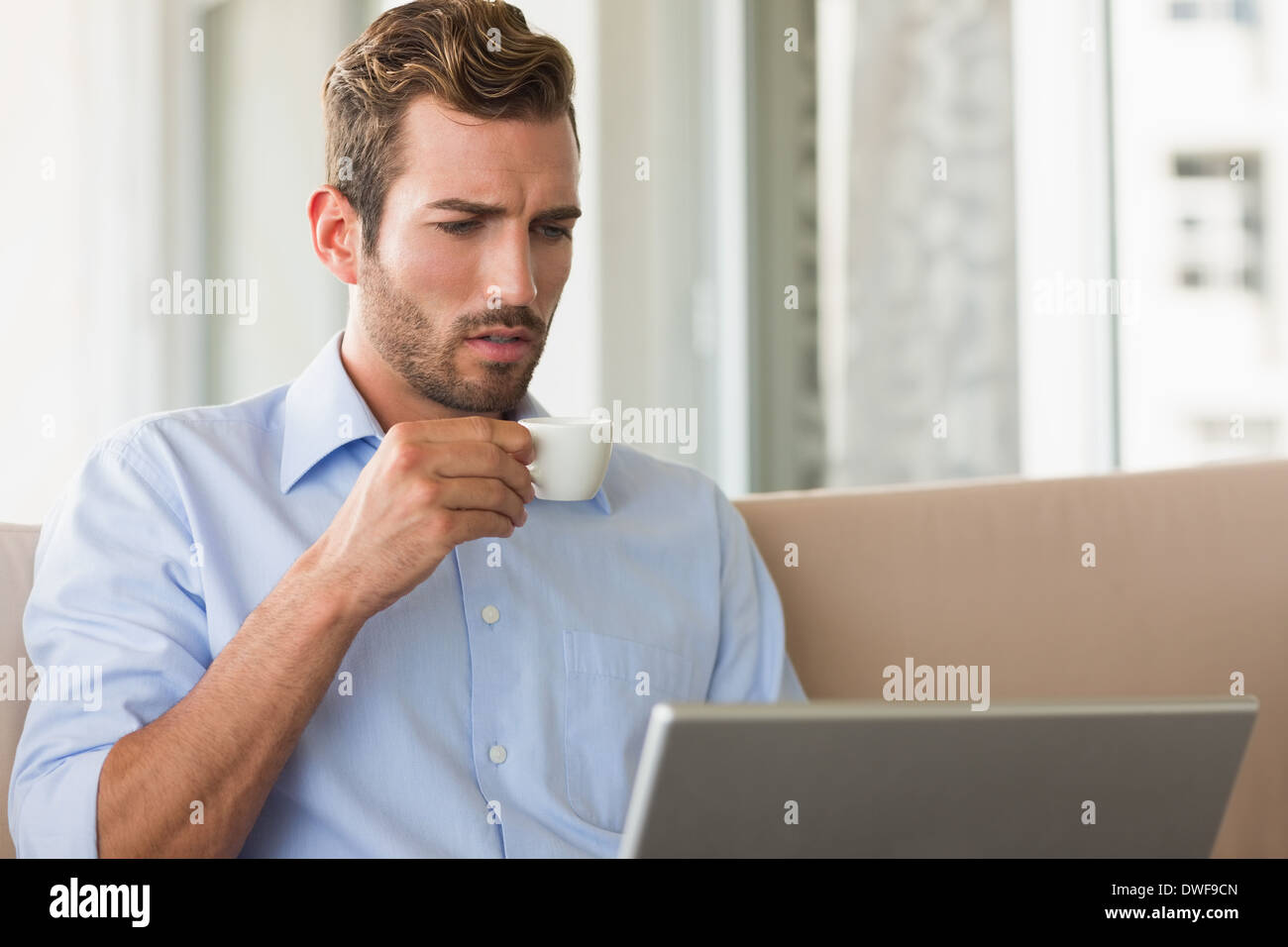 Handsome businessman working on laptop drinking espresso Stock Photo