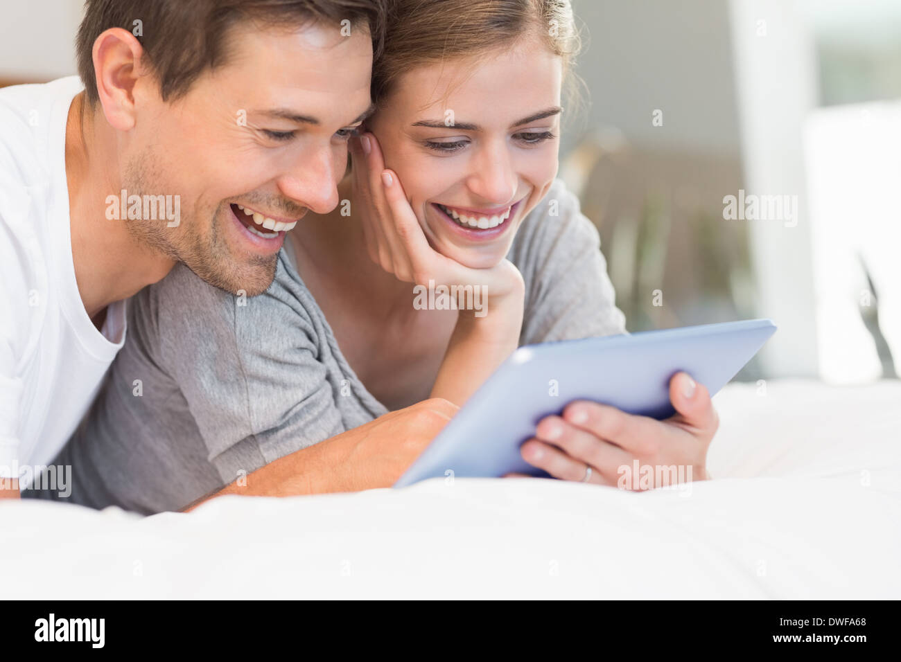 Happy couple on bed using tablet pc Stock Photo