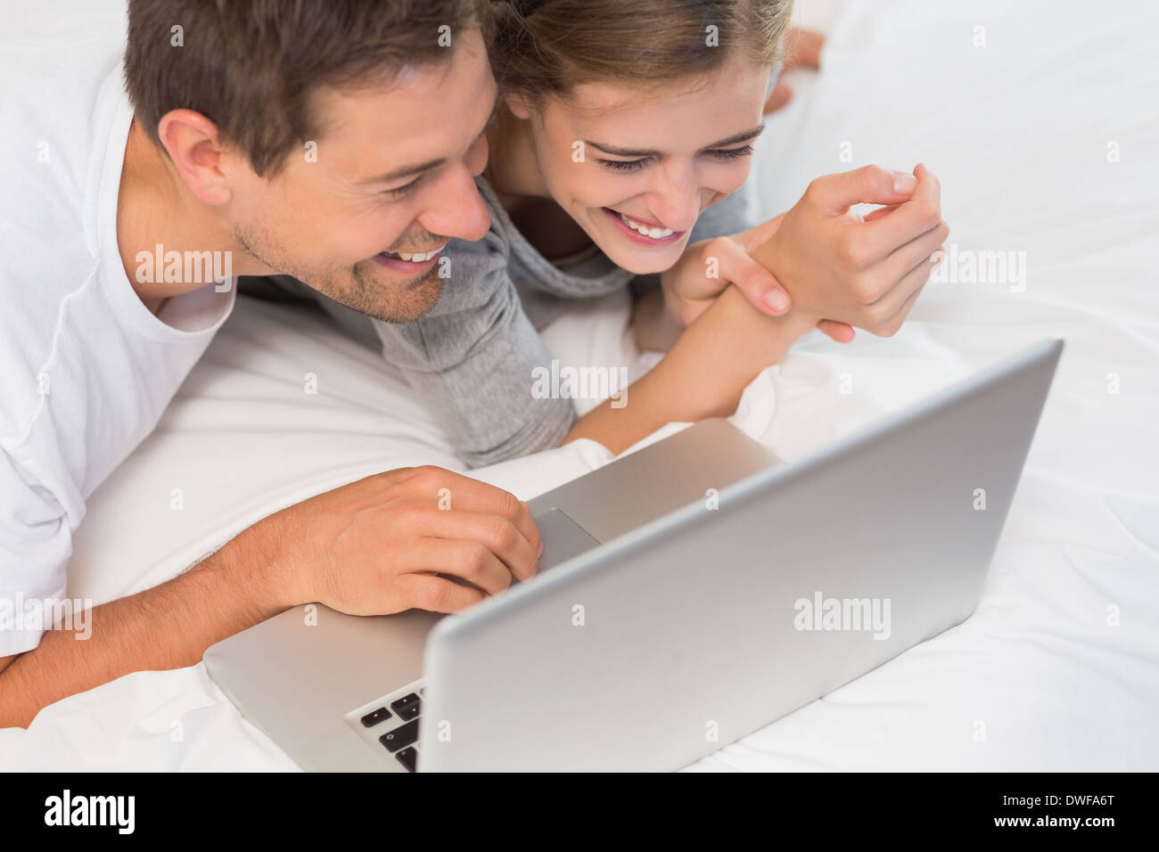 Happy couple on bed using laptop Stock Photo
