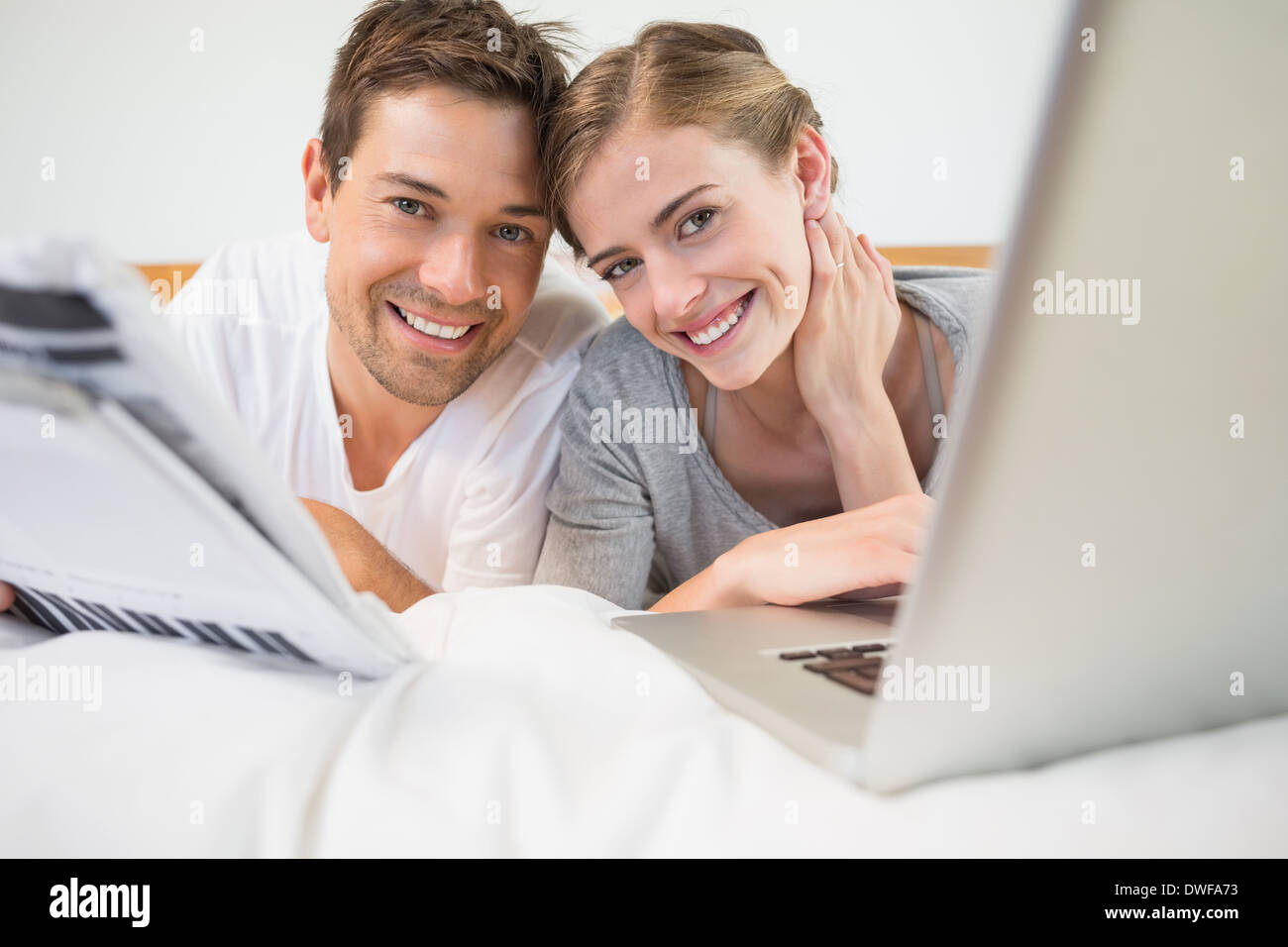 Happy couple on bed using laptop Stock Photo - Alamy