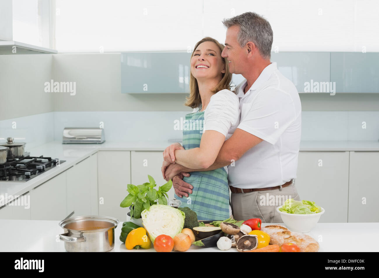 Side view of a man embracing woman in kitchen Stock Photo - Alamy