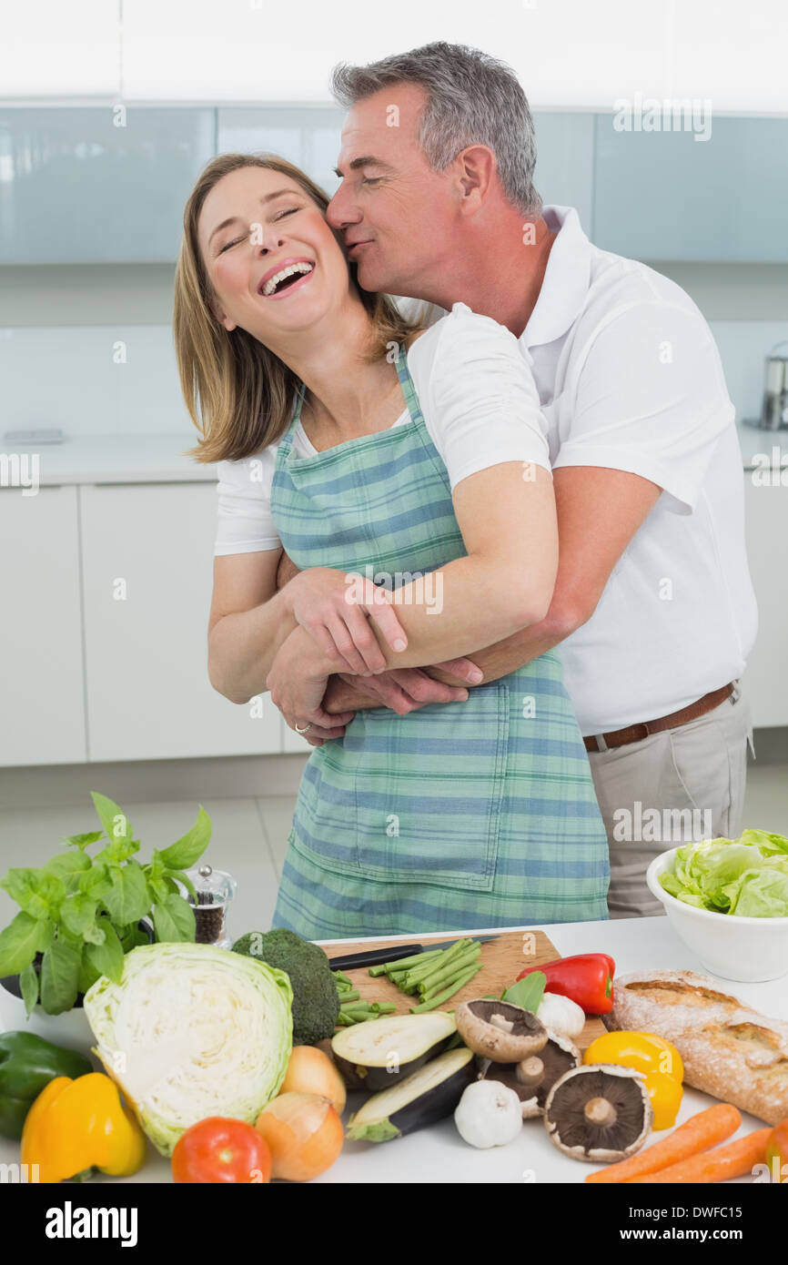 Man embracing and kissing woman in kitchen Stock Photo - Alamy