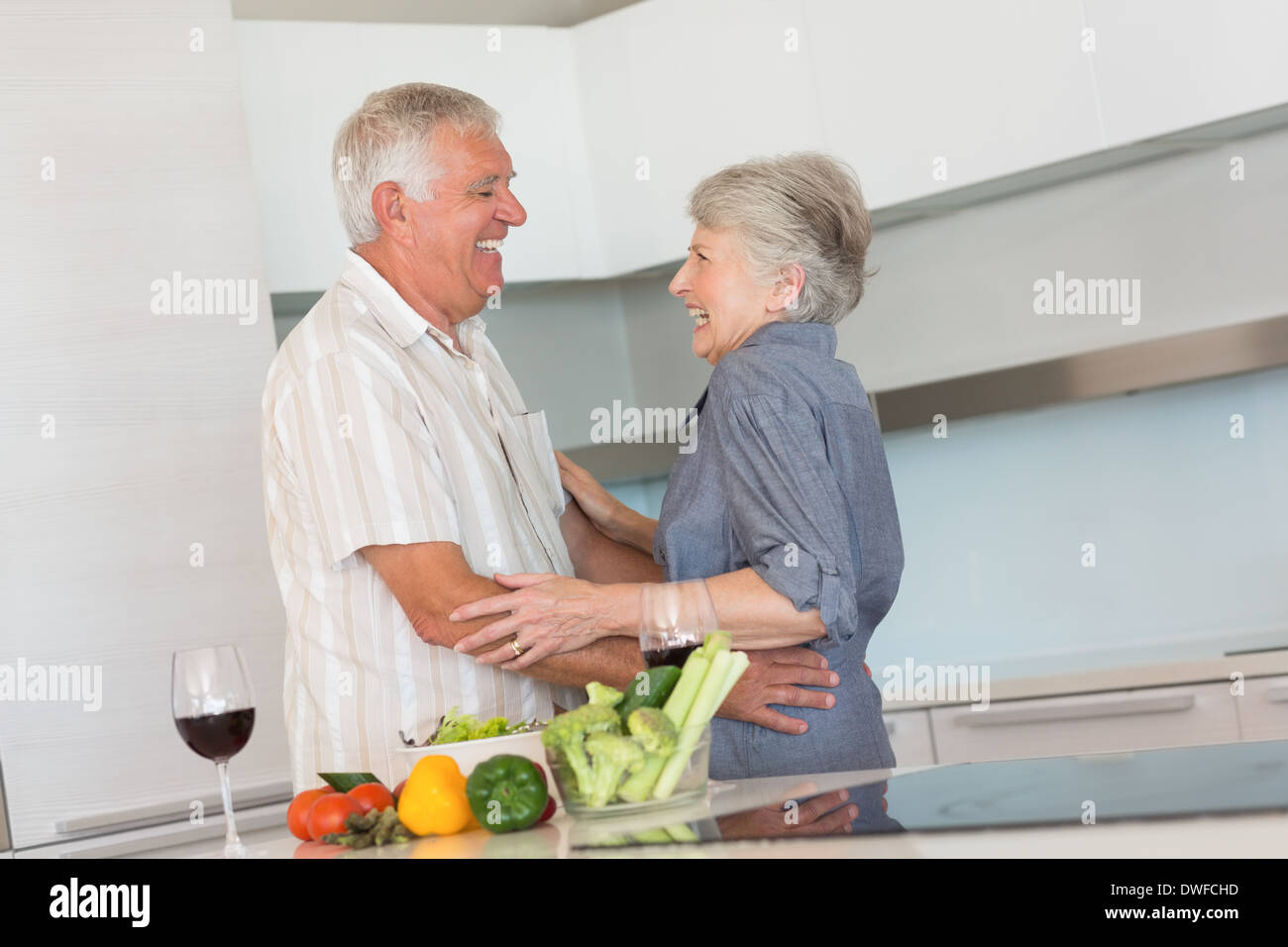 Happy senior couple hugging while preparing a meal Stock Photo