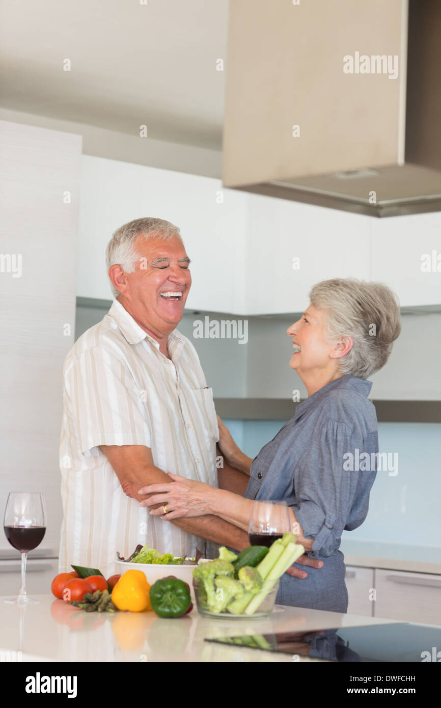 Happy senior couple hugging while preparing a meal Stock Photo