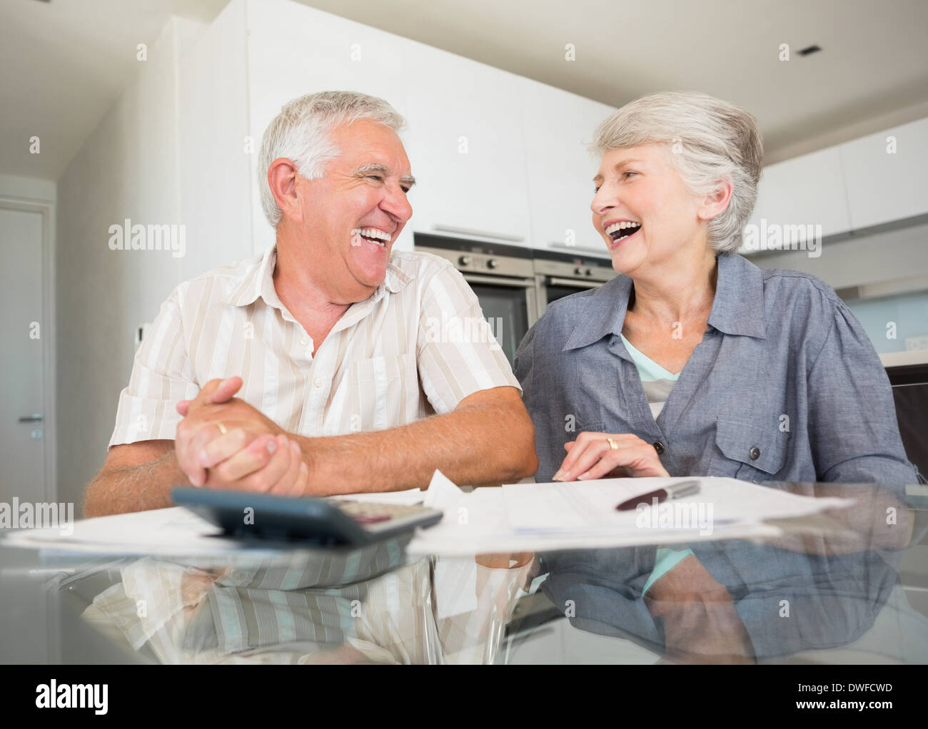 Happy couple using the calculator to pay bills Stock Photo