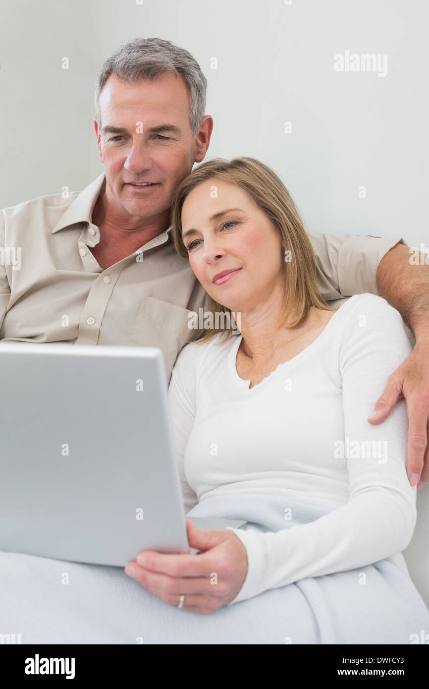 Loving couple using laptop on sofa Stock Photo