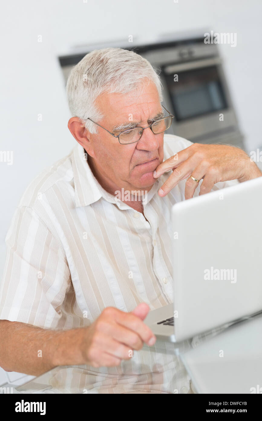 Focused senior man using the laptop at the table Stock Photo