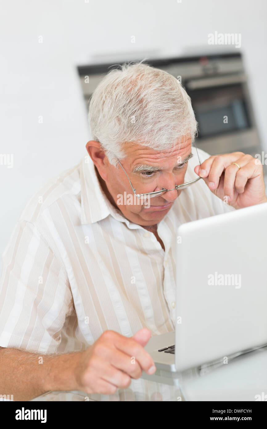 Focused senior man using the laptop at the table Stock Photo
