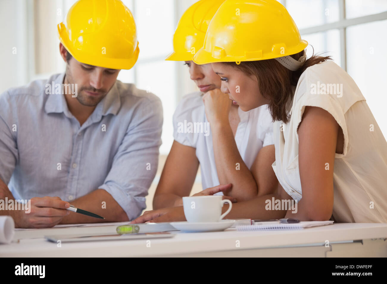 Architects in yellow helmets working on blueprints Stock Photo